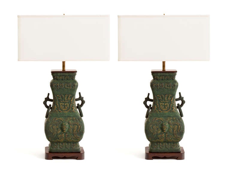 A monumental pair of metal Chinese urn form lamps with gorgeous patinated verdigris bronze finish. Custom carved mahogany bases and tops. Double socketed with solid patinated brass hardware.