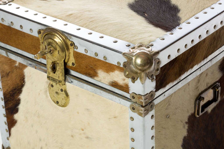 Unusual 1970s cowhide trunk with chrome and brass studded frame. Two brass handles on exterior for added detail.
Retains original key, interior is fully lined and has a tray that rests inside. 
May also be used as an occasional table.