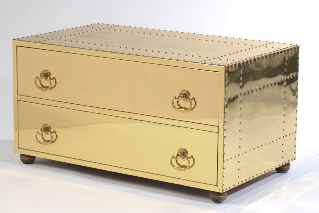 Sarried studded brass chest has two ample drawers for storage with four decorative brass pulls.