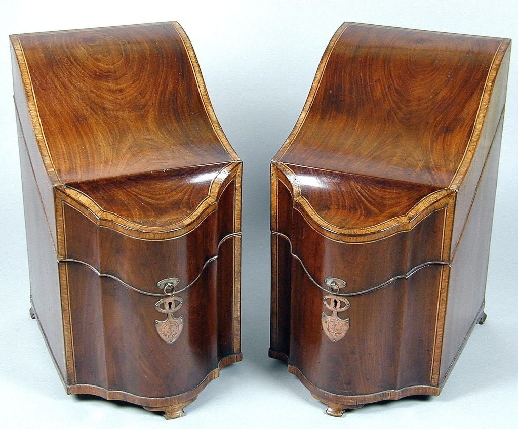 Pair of unusual English Georgian mahogany knife boxes, circa 1780. Each with a shaped sloping cover with satinwood crossbanding and boxwood stringing, the front of serpentine form, raised on short ogee bracket feet; the interior fitted with