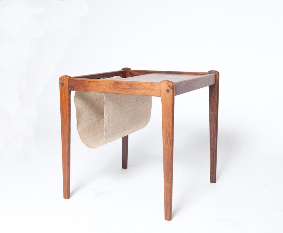 This Lovely teak and linen magazine holder serves as both a table and a magazine rack. Mid century design is marked by its use of simple, clean lines, and organic materials, The warm teak frame and textured linen sling make this item an excellent
