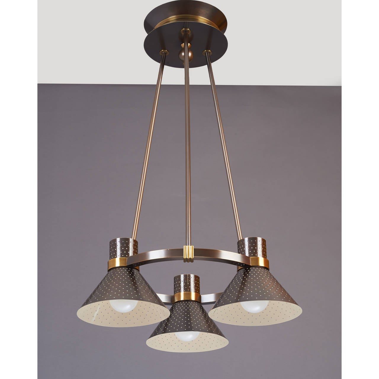 Modernist three-light chandelier with perforated metal shades.
Oxidized and polished bronze mounts.
France, 1950s.
Dimensions: 40 H x 27 Ø.
Rewired for use in the US with 3 standard base bulbs