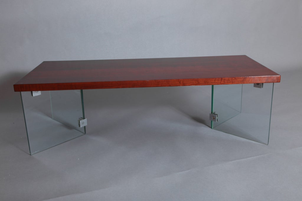 Jacques Dumond (1906-1988)
Modernist coffee table in mahogany stained French walnut, raised on tempered glass legs by Saint-Gobain, and nickel bronze mounts. Glass impressed Securit glace
France, 1950s
Dimensions: 47 x 20 x 14 H.