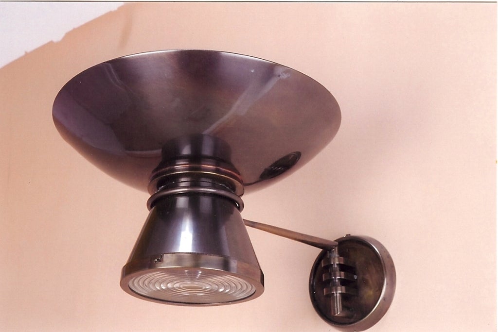 Frankreich, 1950er Jahre
Einzelne Gelenkarmleuchte aus patiniertem Metall mit Fresnellinse, mit nach oben und unten gerichteten Lichtern
Umverdrahtet für den Einsatz in den USA mit einer oberen und drei unteren Glühbirnen
14 Durchmesser x 9 H x 20