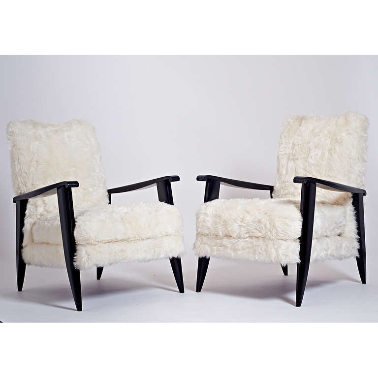 France, 1950s.
A sculptural pair of black shellacked wood armchairs with elegant carved scroll arm and sabre legs; later mock sheepskin upholstery 
25 W x 28 D x 17 / 32 H.