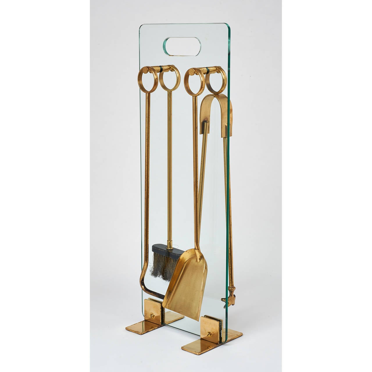 A set of four brass fireplace tools
mounted on a glass panel with inset handle and bronze feet,

France, 1970s.

Measure: 10 x 26 x 6 D.