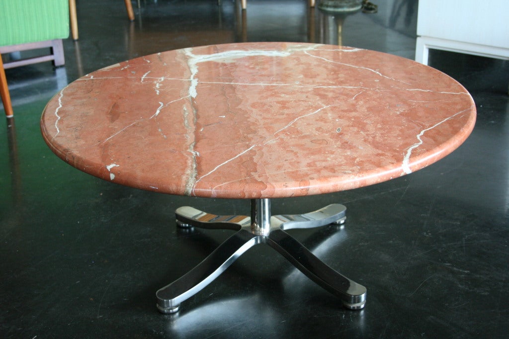 A beautiful marble top coffee table on a stunning polished heavy stainless steel base designed by famed Greek designer, Nicos Zographos. The original marble top is stunning with a few natural fissures, giving the marble a very organic look.  Marble