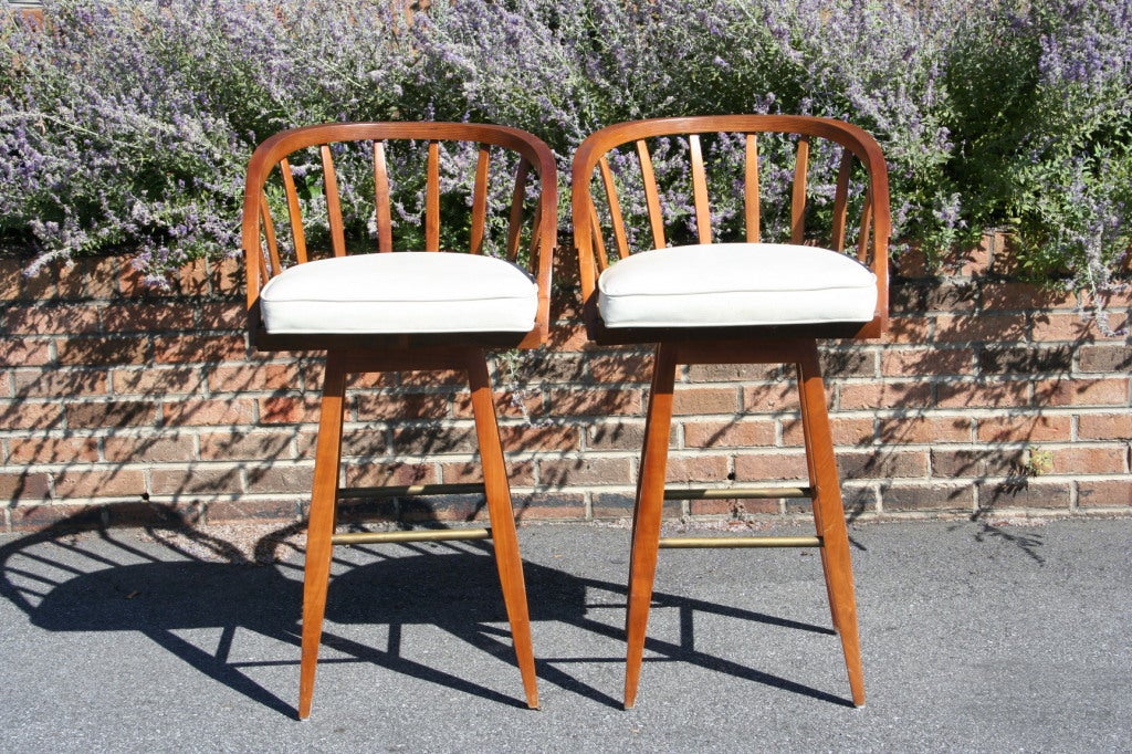 An extremely rare pair of barstools designed by Edward Wormley for Dunbar Furniture.  Walnut frames are accented with brass footrests and a 2