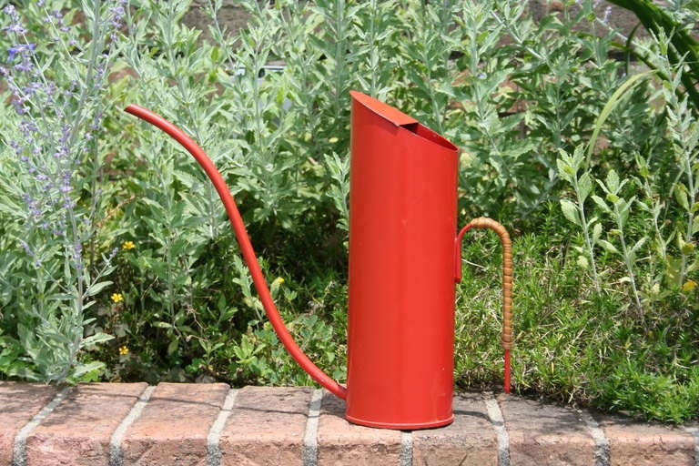 A beautifully designed red enameled metal watering can, produced by Ystad Metal, Sweden. Metal handle is wrapped with rattan, creating a nice contrast in materials. 