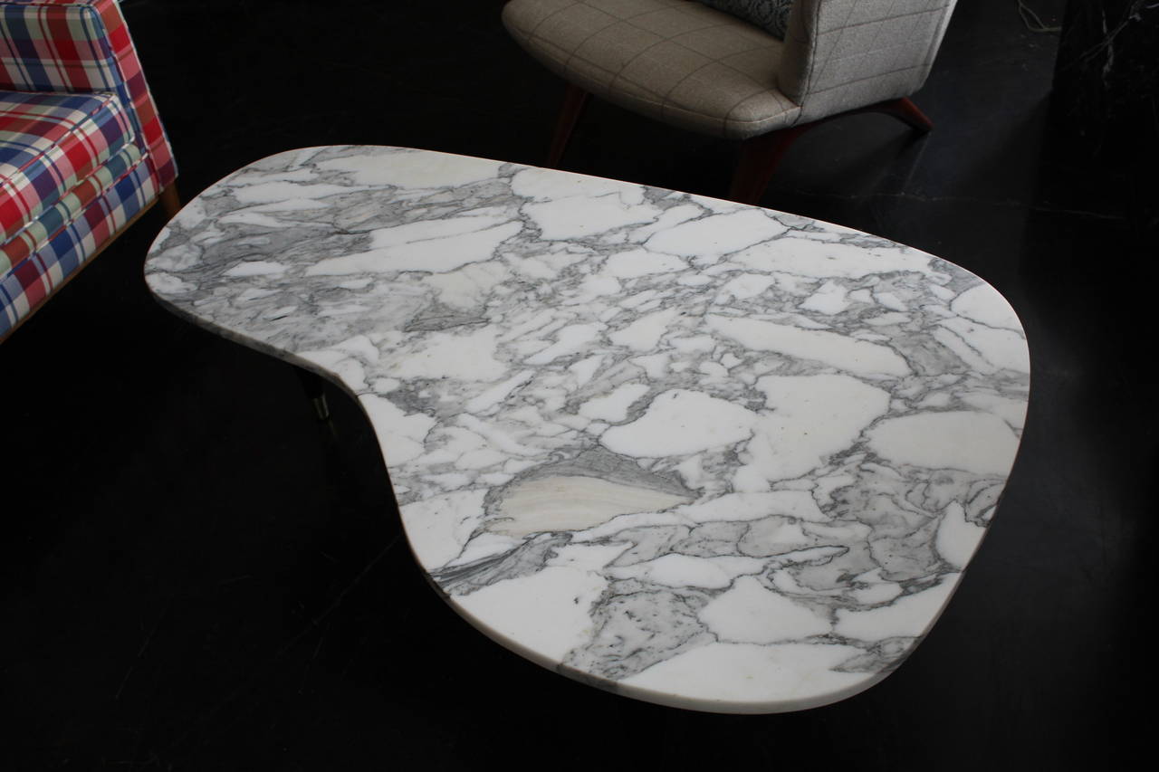 Beautiful Italian cocktail table with a finely polished carrara marble top, ebonized base and brass capped feet. The white marble top contrasts well with the clean ebonized base.