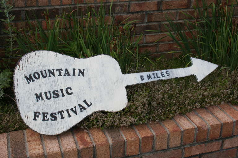 Vintage Mountain folk art music festival sign, painted and stenciled plywood shaped into a guitar.
