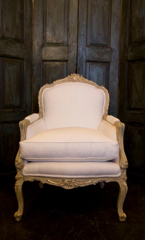 Pair of carved french arm chairs gilded and painted. Upholstered natural white stripe linen.
