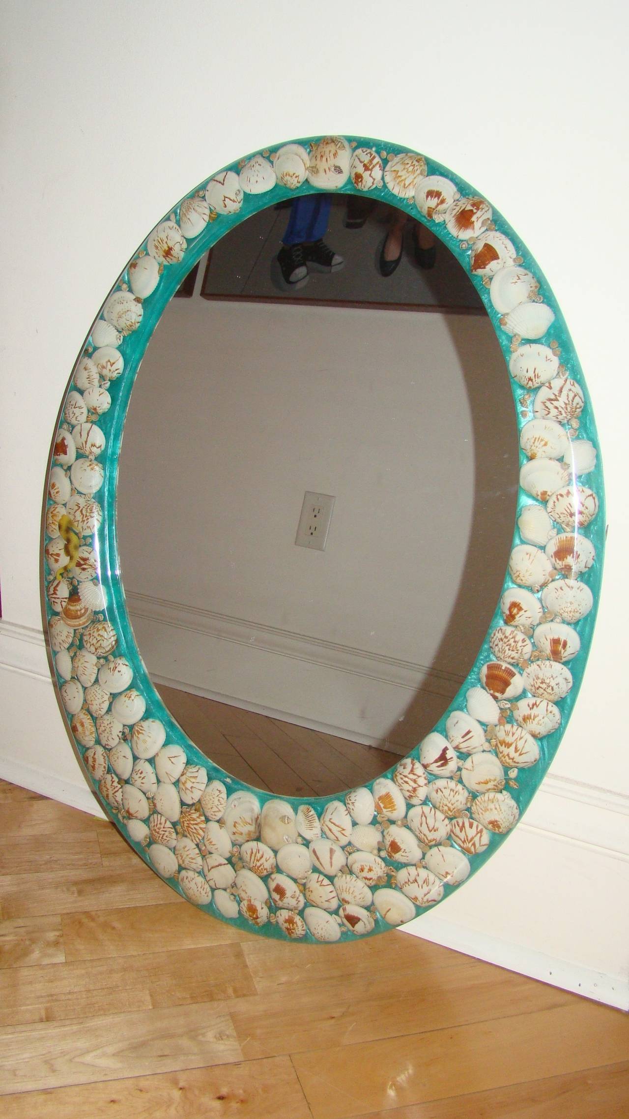 Terrific Mid-Century Lucite wall hanging mirror. This beautiful design is comprised of various sea shells internally imbedded in the Lucite with aqua color background. Truly a beautiful and unique mirror.