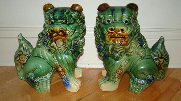 Great pair of Mid Century Glazed Pottery Foo Dogs. Each is comprised of a hand painted glazed pottery in green with brown and blue accents. Fine addition to your modern decor.