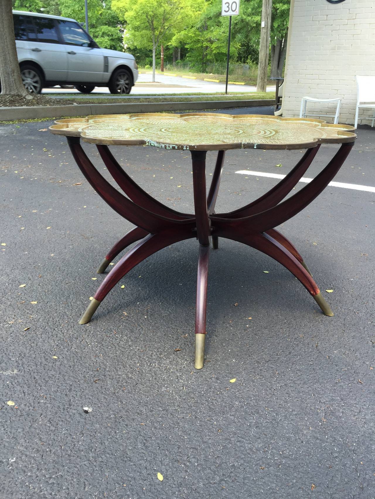 Beautiful Mid-Century wood and brass coffee table. This interesting design is comprised of a sculptural wood base with brass feet and removable brass tray top. The top has a Fine etched design inlaid in the brass. The base can fold up for storage