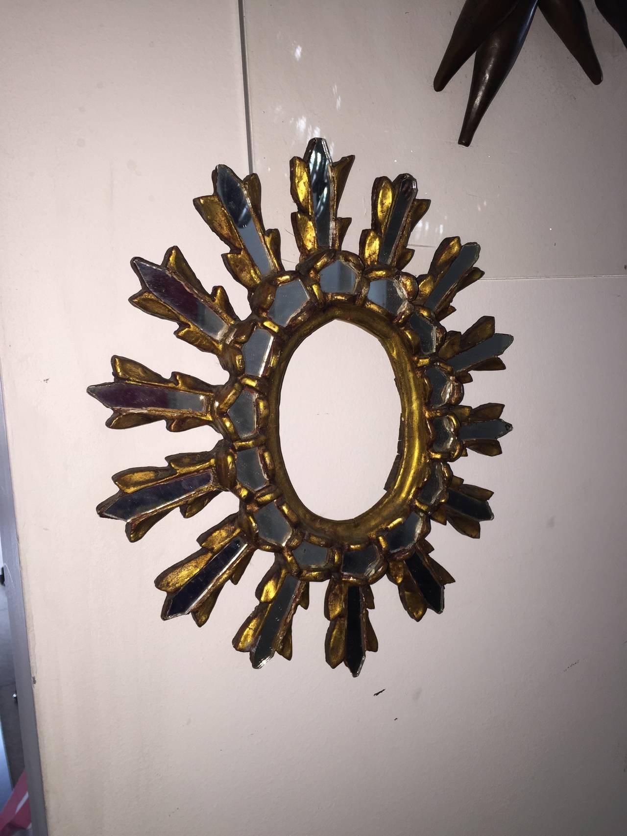 Exceptional Antique Sunburst wall hanging Mirror much in the style of Vautrine.  This unusual design is comprised of gold guilded wood and plaster in a sculptural sun shaped frame with embeded mirror pieces. It is very old and does not appear there