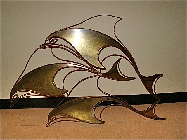 Terrific Mid Century Wall Hanging Sculpture by Curtis Jere. This interesting piece is comprised of sculpted brass depicting a group of 3 dolphins. Signed and dated C Jere. Truly a beautiful sculpture in person.