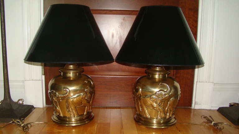 Outstanding pair of Brass Table Lamps by Federick Cooper. These beautiful lamps depict a group of Elephants on each and are complete with original black Frederick Cooper Lamp shades and Finials. Truly a special pair of lamps.