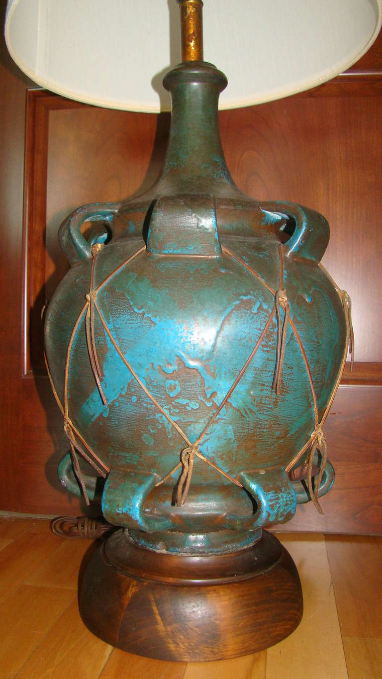 Terrific large scale Italian pottery table lamp in the manner of Fantoni or Gambone. Comprised of hand painted and glazed heavy sculptural pottery with leather wrapped design and wood base. Complete with original shade and finial.