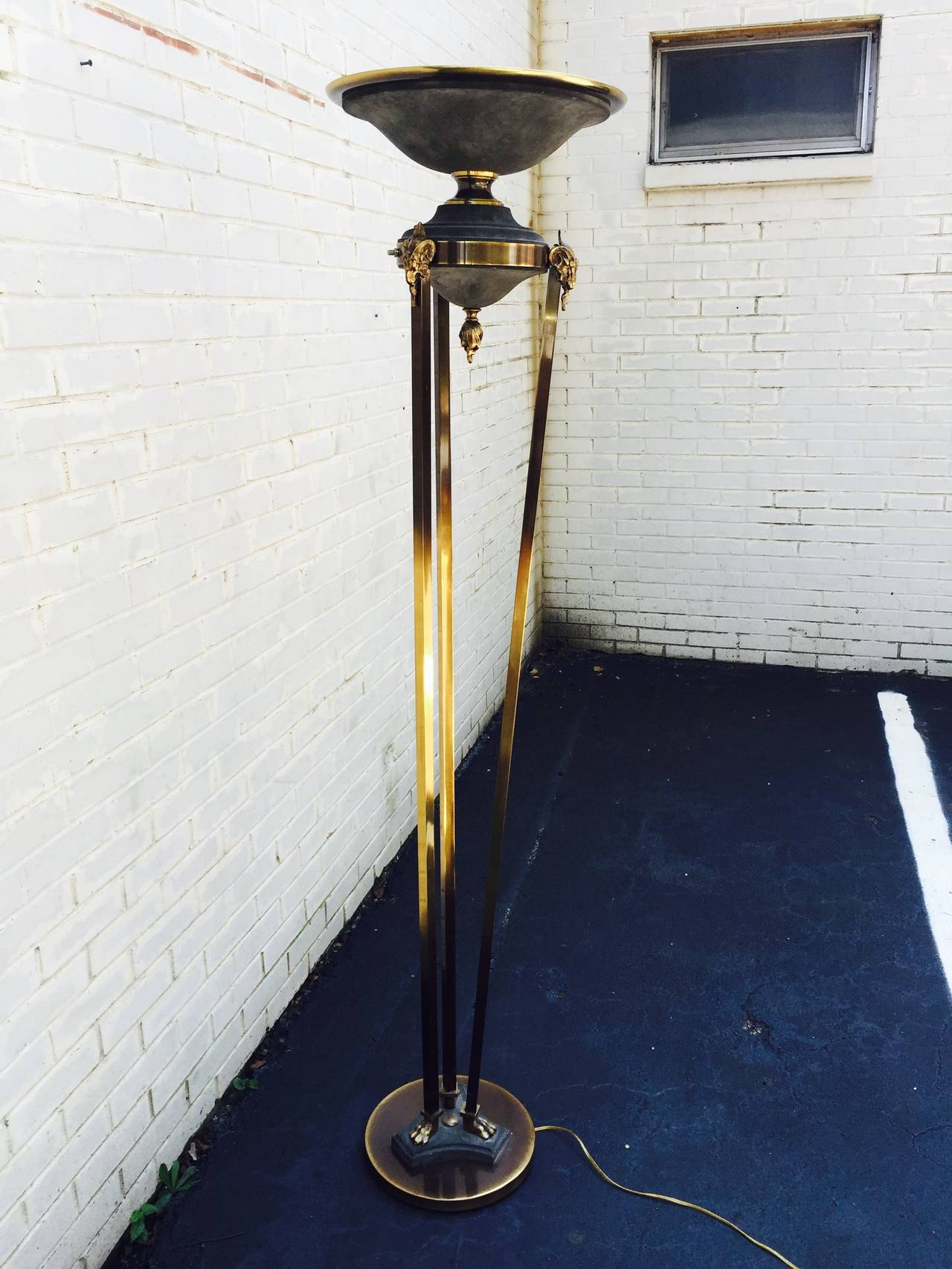 Terrific Sculptural Brass Torchiere Floor Lamp in the style of Jansen. Comprised of three brass ram's-heads with hoof foot design. Fits a Halogen bulb.