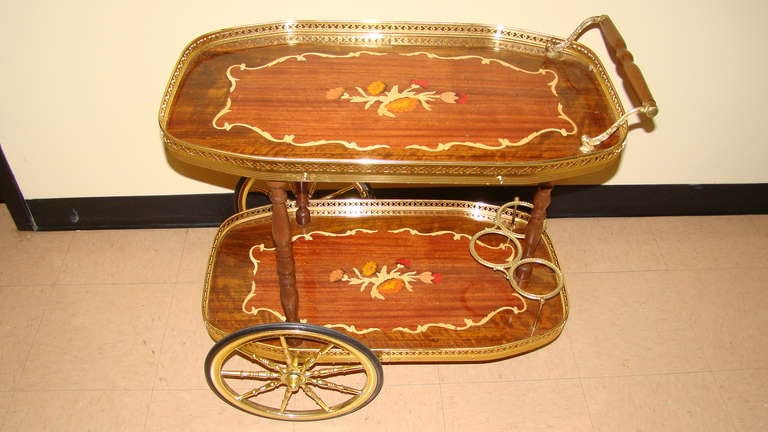 Beautiful Mid Century Italian Bar Cart. This interesting piece is comprised of Inlaid lacquered wood with brass accents and wheels. Signed Made in Italy