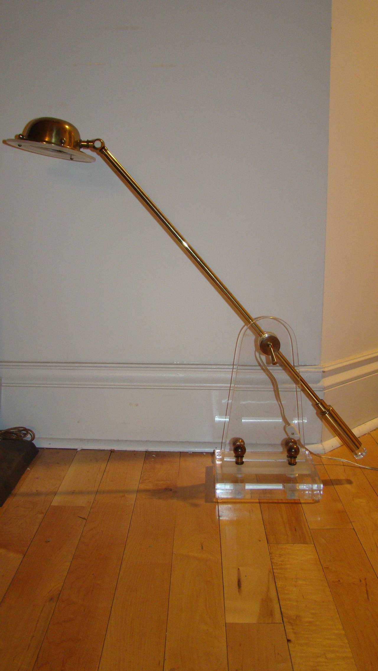 Terrific Mid-Century Lucite and brass desk lamp. This beautiful design is comprised of a crystal clear Lucite base with adjustable brass and Lucite arm. The lamp takes a halogen bulb and has a metal transformer switch. Truly a beautiful design in