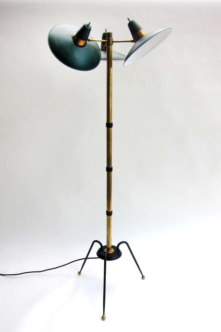 An unusual floor lamp of iron and brass with 3 lacquered metal shades that rotate allowing adjustment and play of light.  A simple yet strong design of bold elements.