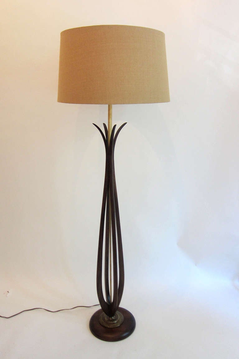 4 sinuous mahogany ‘stems’ around a brass pole sitting on a base of brass and mahogany form a very simple yet elegant floor lamp. Shade is a light beige linen. 
(Base is 10