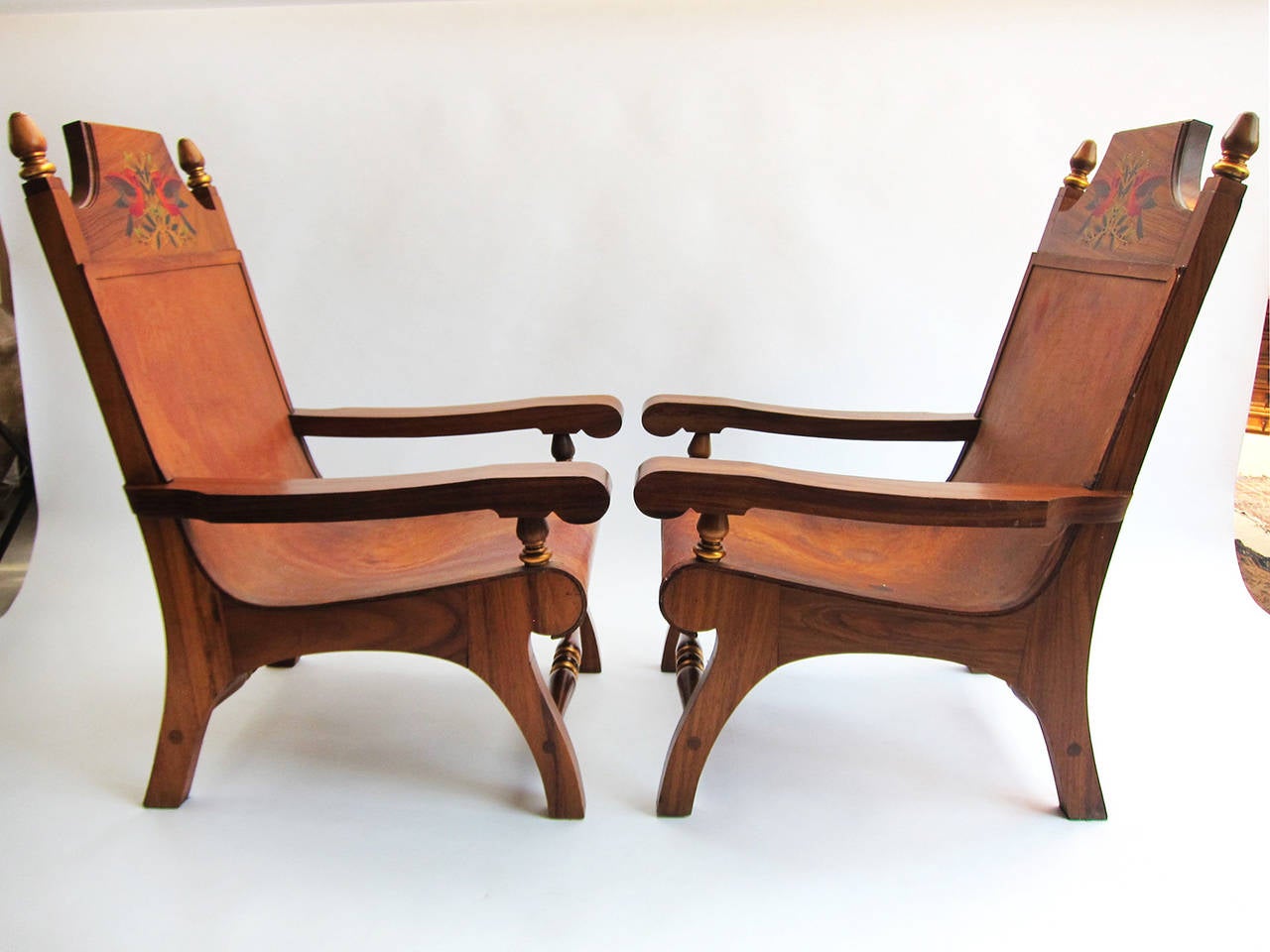 A very nice pair of armchairs made from tropical perota wood with hand-painted head supports, gold leaf detailing and leather seats by Alejandro Rangel Hidalgo (whose style was known as “Rangelino”). 
Rangel Hidalgo (1923-2000) was an artist,