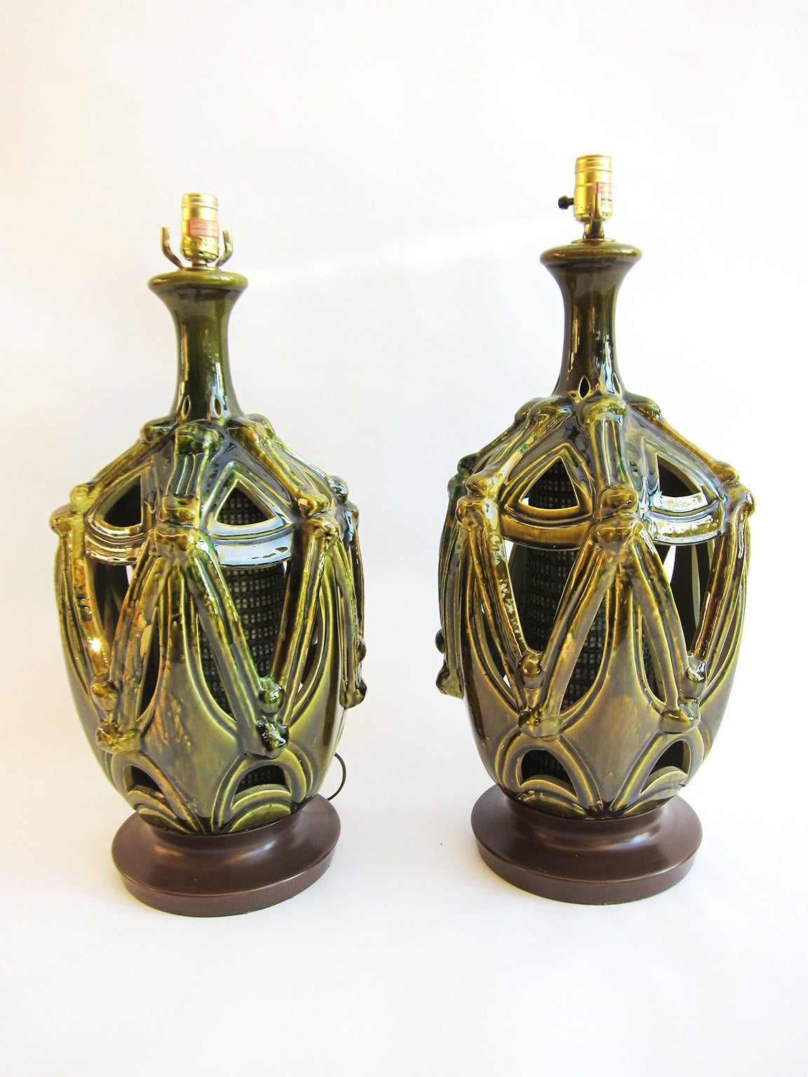 A handsome pair of cut-out glazed ceramic lamps with some areas showing a chorreado (drip) effect with a mesh interior lantern. Lamps sit on a nicely patinaed brass base. A stunning pair, especially when lit. (See photo)
It is quite possible that