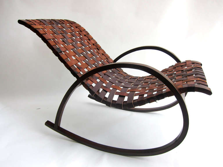 This rocking chair boasts a simplicity of form rendering the piece sculptural in essence. The 2 contoured veneered mahogany plywood arms, support the seat frame which is tacked with cowhide strapping. From the 50’s and following the principles of