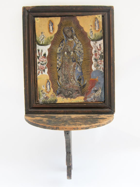 Framed oil painting on zinc of the Virgen de Guadalupe which is mounted on a ‘repisa’ where candles and flowers could be placed in offering. <br />
This retablo seems to tell the story of a boy to whom the Virgin appeared. Through their dialogue,