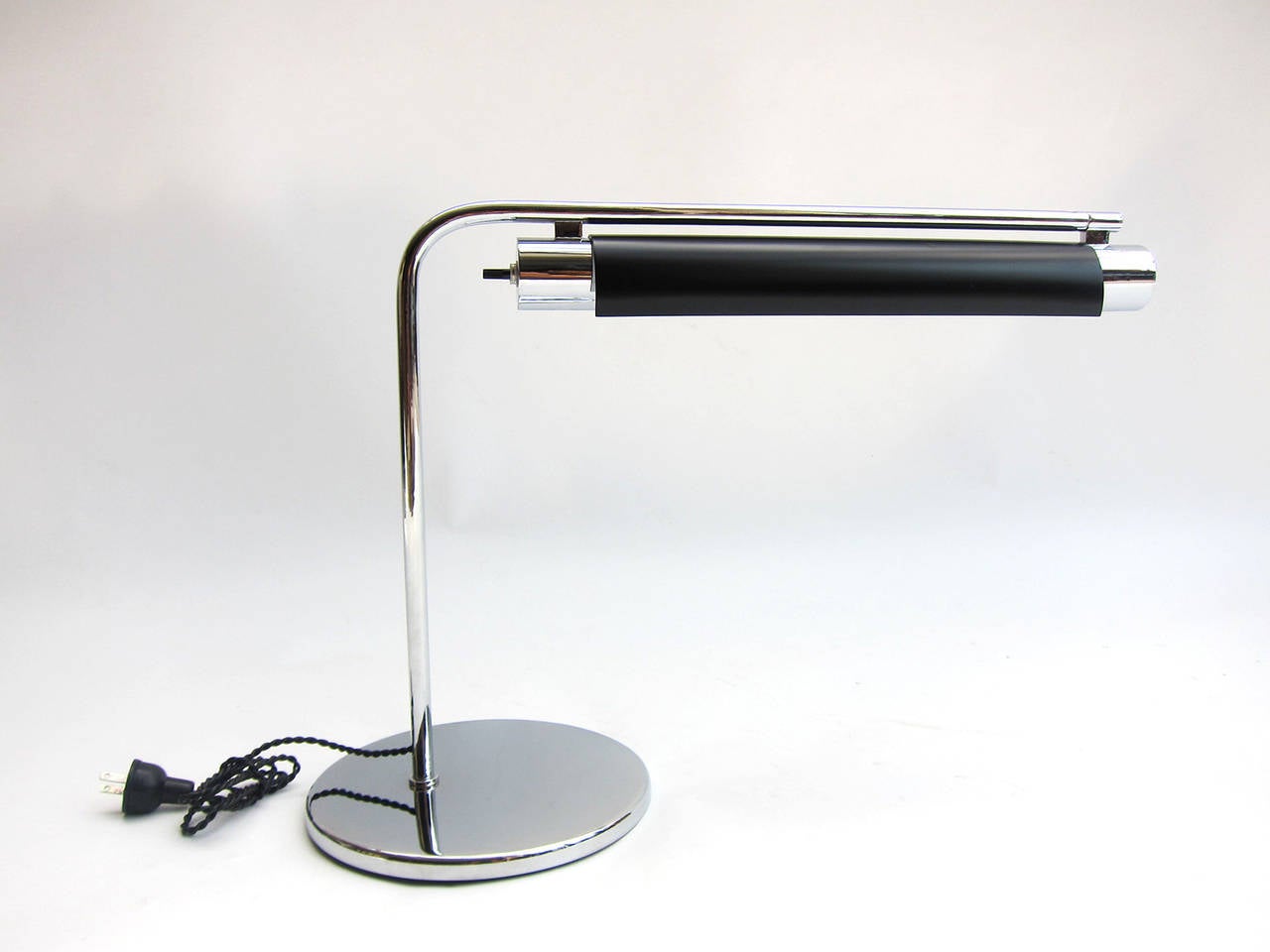 Very sleek desk lamp of chromed steel and lacquered metal. Clean, uninterrupted lines lend a bold elegance in the tradition of the modernists. (Base measures 8.20” in diameter).