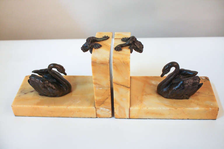 A stunning pair of marble and bronze bookends from France. An aquatic scene is beautifully rendered in bronze; the swans seem ready to glide across the marble as if it was water, while above; a pair of frogs perch. These bookends are truly unique