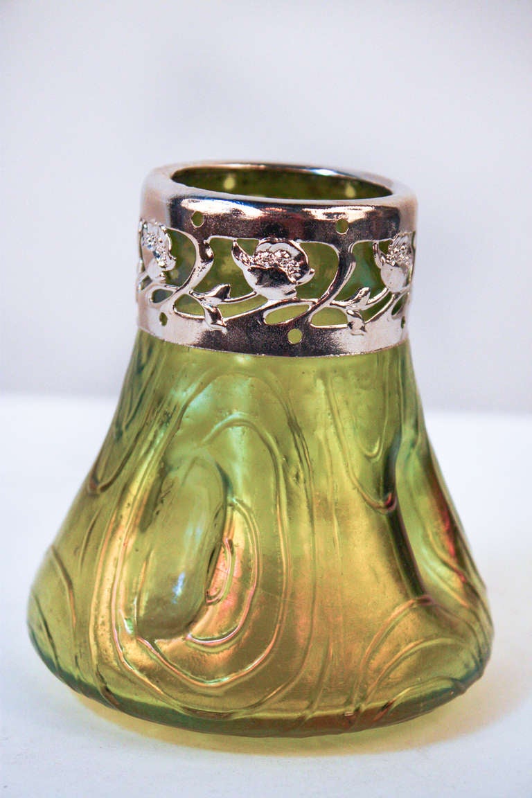 A beautiful bohemian art glass vase. Made in the style of world renowned Loetz glassmakers in the Czech Republic, this stunning vase features a translucent yet vibrant green glass, and polished nickel overlay top rim. This is a great piece, as