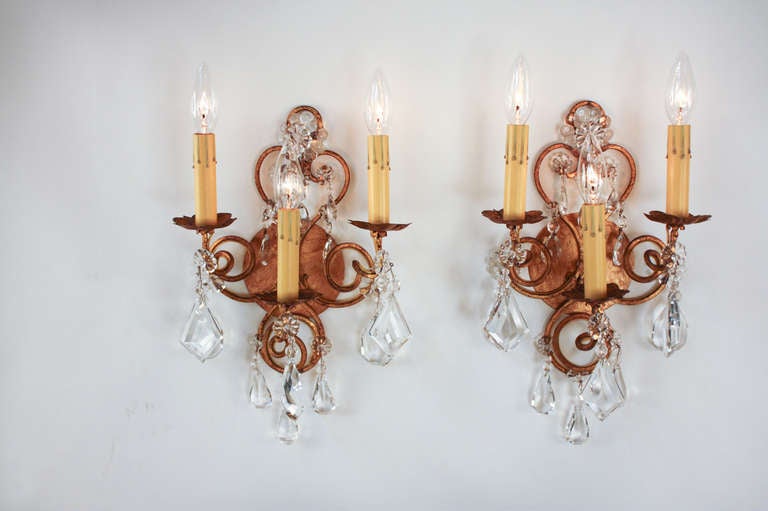 A beautiful pair of mid-century three light wall sconces. Made in Italy, these stunning sconces feature a gilded metal and crystal design.