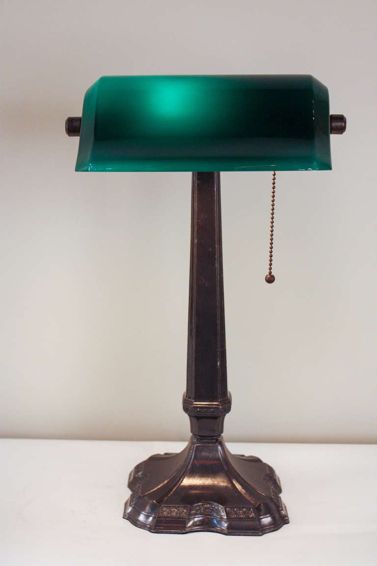 L'indispensable lampe de table américaine. Cette lampe classique a été fabriquée au début du siècle dernier:: et présente un bel abat-jour vert et une finition en bronze.