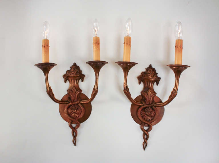 A beautiful pair of Art Deco wall sconces. Made in France during the 1920's, these sconces are made of solid bronze. Elegantly detailed with classic Caduceus design (very similar to the universal symbol for medicine), these sconces are truly unique.