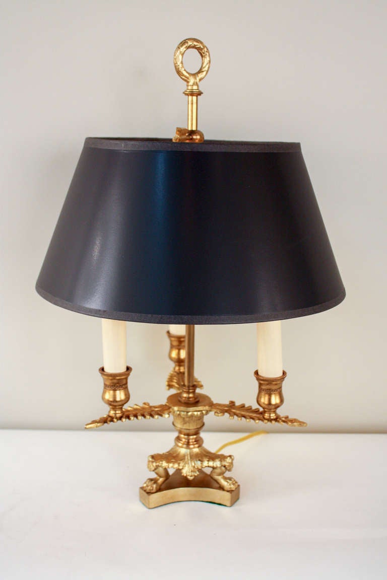 A beautiful bouillotte table lamp . Made at the beginning of the last century, this fantastic bronze lamp is filled with elegant detail. Adorned with a classic adjustable black shade with gold lining, three lights and a fantastic finial top off this
