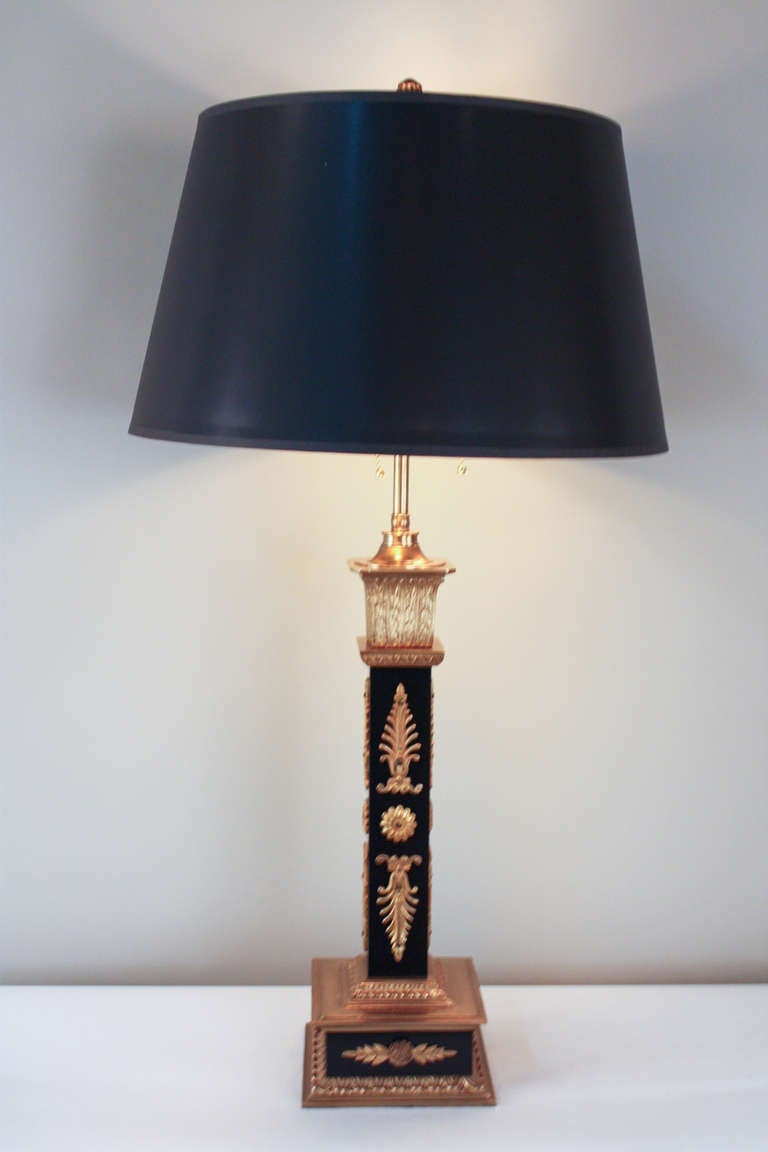 A classic Empire Style table lamp from France. Made of beautiful black lacquer and bronze, this piece is simply gorgeous. A versatile double light lamp: the height is easily adjustable. A black shade with gold lining tops off this elegant lamp.
