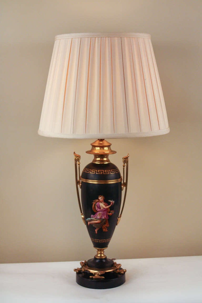 Crafted in France during the 19th century, this neoclassical porcelain table lamp features beautiful bronze mounting and an elegant pleated silk shade. Originally an oil burning lamp, this handpainted piece has been professionally electrified. An