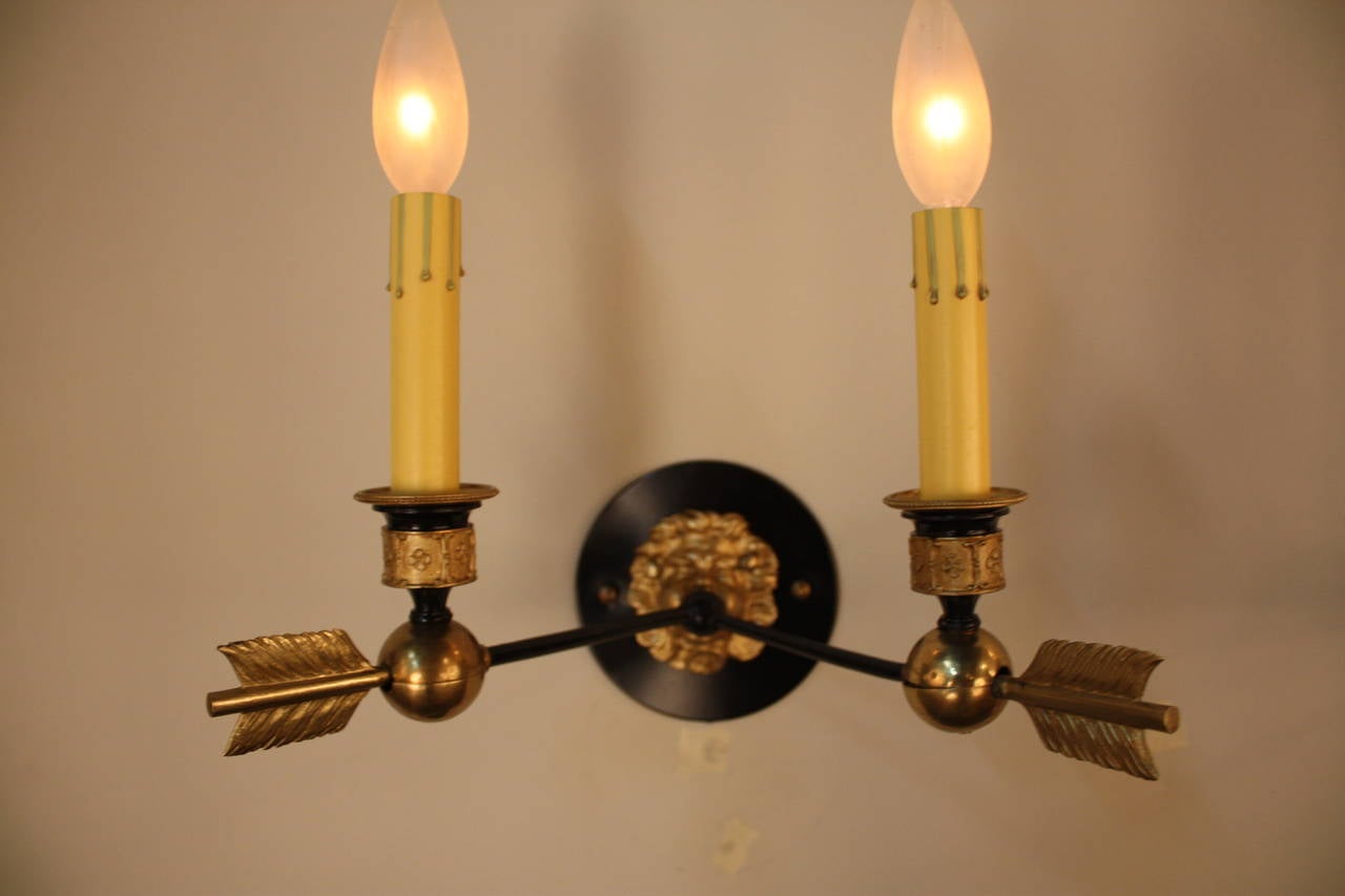 French made in the traditional Empire style, this elegant pair of gas electrified wall sconces features a beautiful bronze and black lacquer design. Masterfully crafted pairs of bronze arrows coming out of baby's mouth which the end of arrow was