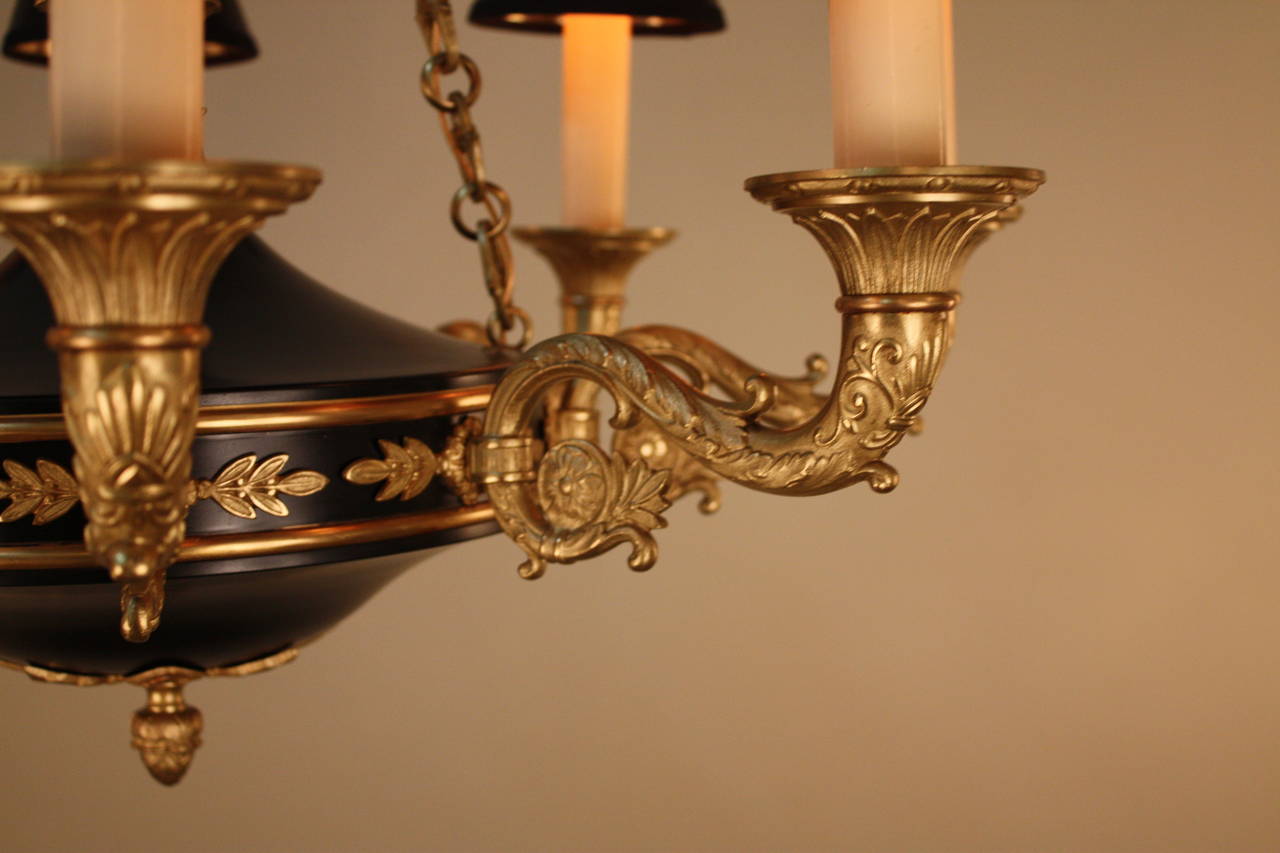 Crafted in France during the 1930s, this stunning chandelier features eight lights and fantastically detailed bronze work and a beautiful black lacquer body. Amazing bronze detail work can be found throughout the piece, with small accent pieces that