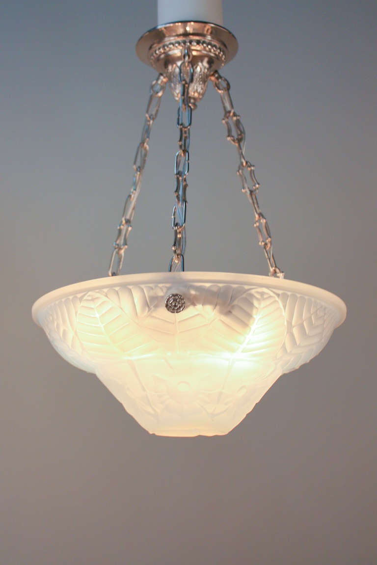 Made at the height of Art Deco by the world renowned French design firm Charles Ranc, this chandelier is beautiful combination of classic European artistry and craftsmanship. 

A thick pressed-moulded opalescent glass shade with an inlaid design