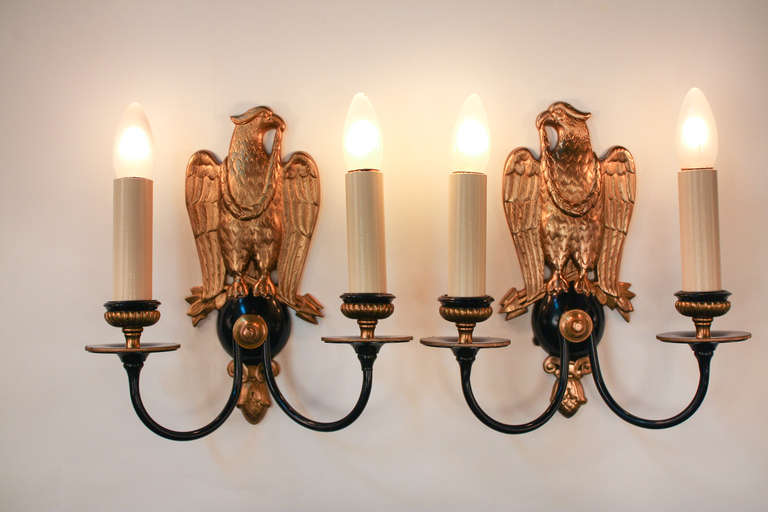 A beautiful pair of wall sconces. Made in America, this pair of sconces feature a classic Federalist-inspired eagle back plate design. Made of black lacquer on bronze, these sconces are both classic yet timeless.