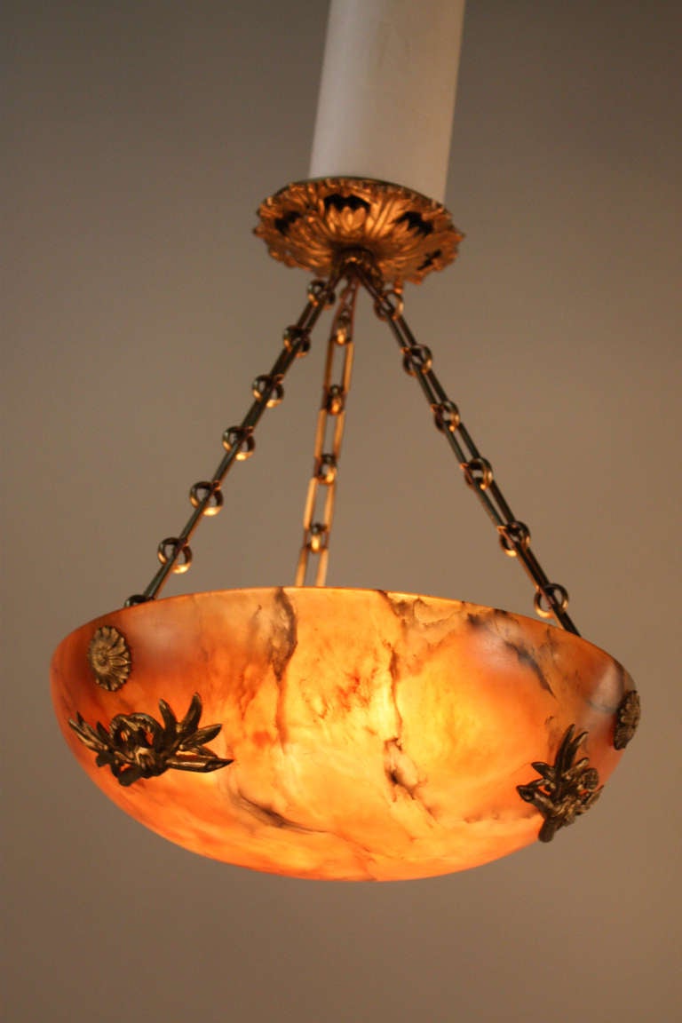 A solid piece of beautiful alabaster serves as the magnificent and vibrant centerpiece of this stunning chandelier. This elegant six light chandelier was masterfully crafted in France during the 1920's, and features gorgeous grain and exceptional