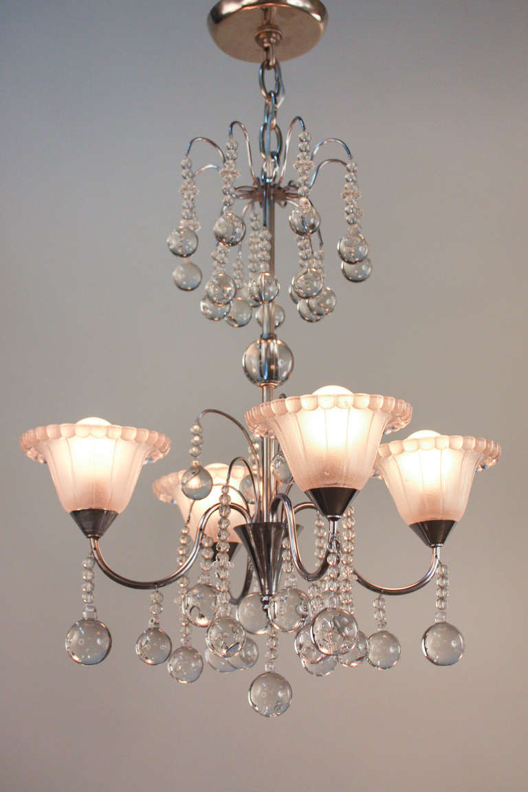 A beautiful Mid-Century Modern piece with Art Deco influences, this 4 light fixture is truly stunning. Made of classic chrome over bronze, this chandelier features dozens of elegant raindrop crystals, ornately decorating the chandelier from top to