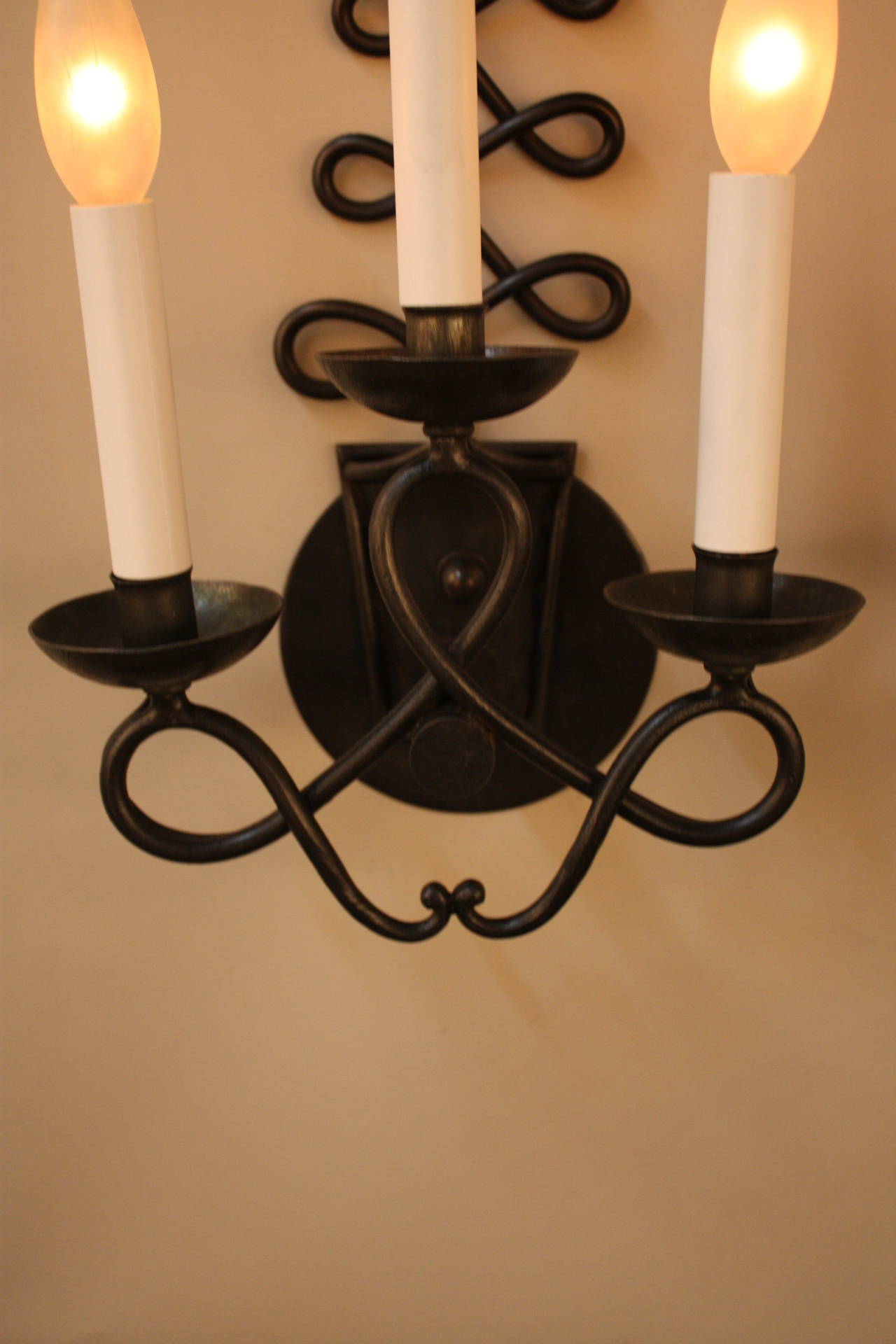 Fabulous pair of Wrought French wall sconces. This pair of uniquely design wall sconces has three light an and has been modified for USA installation.