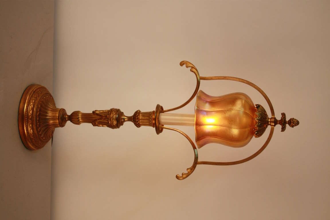 A beautiful bronze lamp, crafted in France at the turn of the last century. Ornate detail work from top to bottom and a brilliant gold art glass lampshade make this piece truly exceptional.