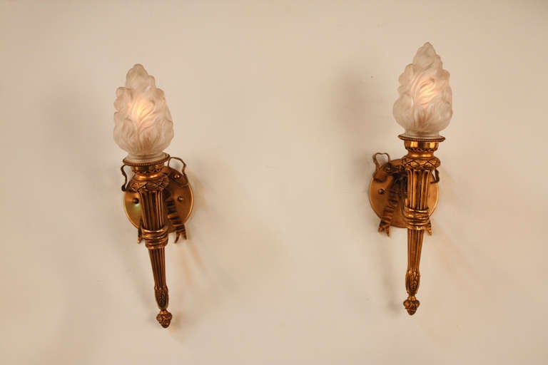 A fantastic pair of 1930's wall sconces that looks as stunning today as the did nearly a century ago. These sconces feature an elegant torch design. Made of ornately detailed bronze, these sconces are topped off by unique and masterfully crafted